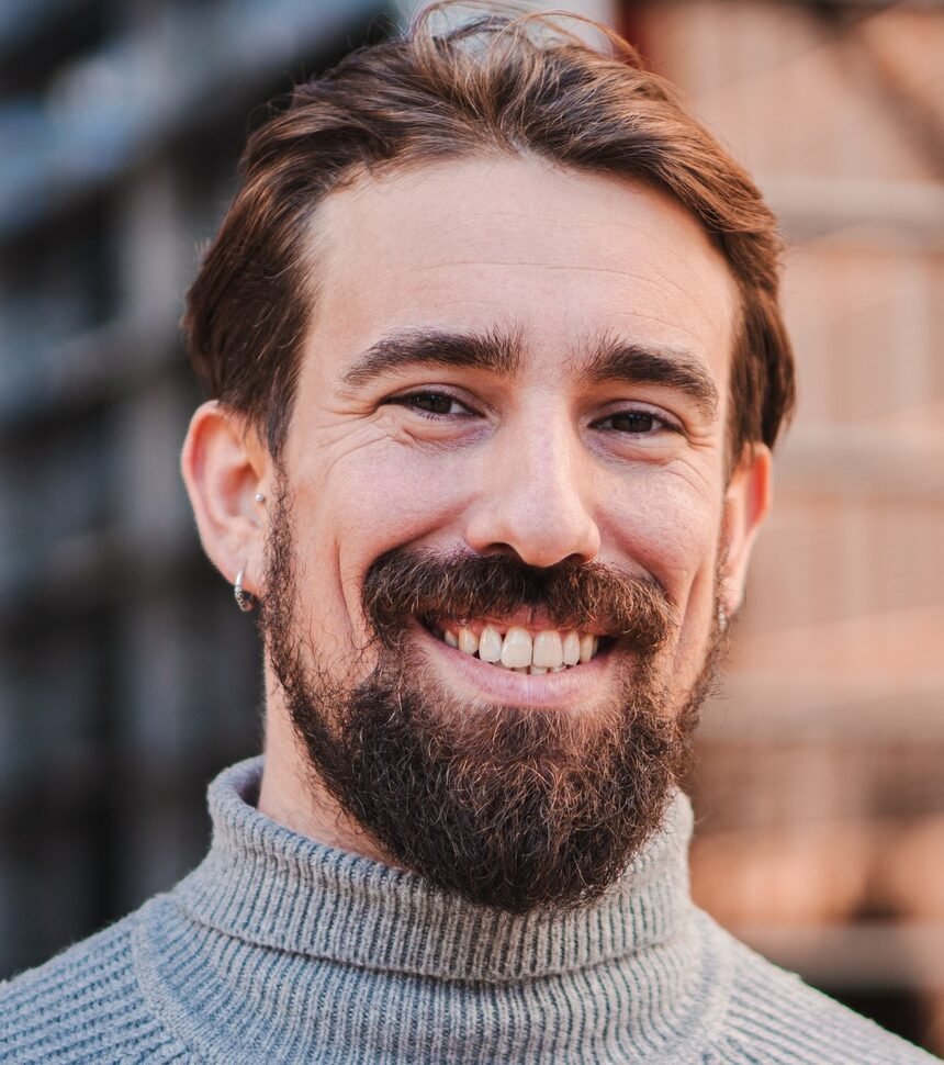 Close up portrait of awesome young caucasian male smiling and looking at camera at the background