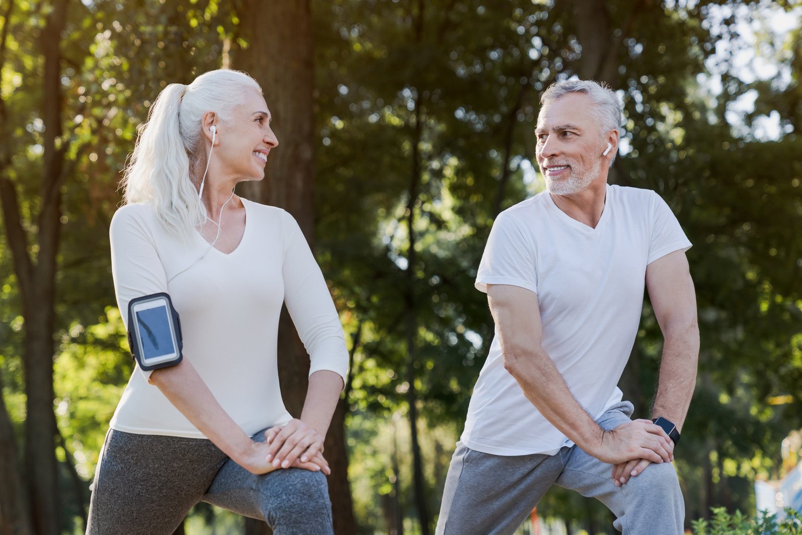 Low angle view of smiling senior couple doing warm up exercises while standing in park